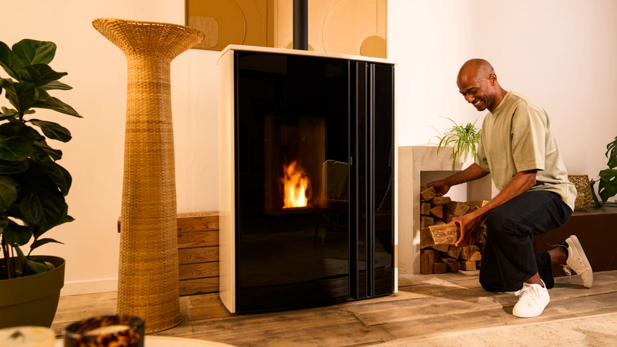 homme qui tient des bûches devant son poêle