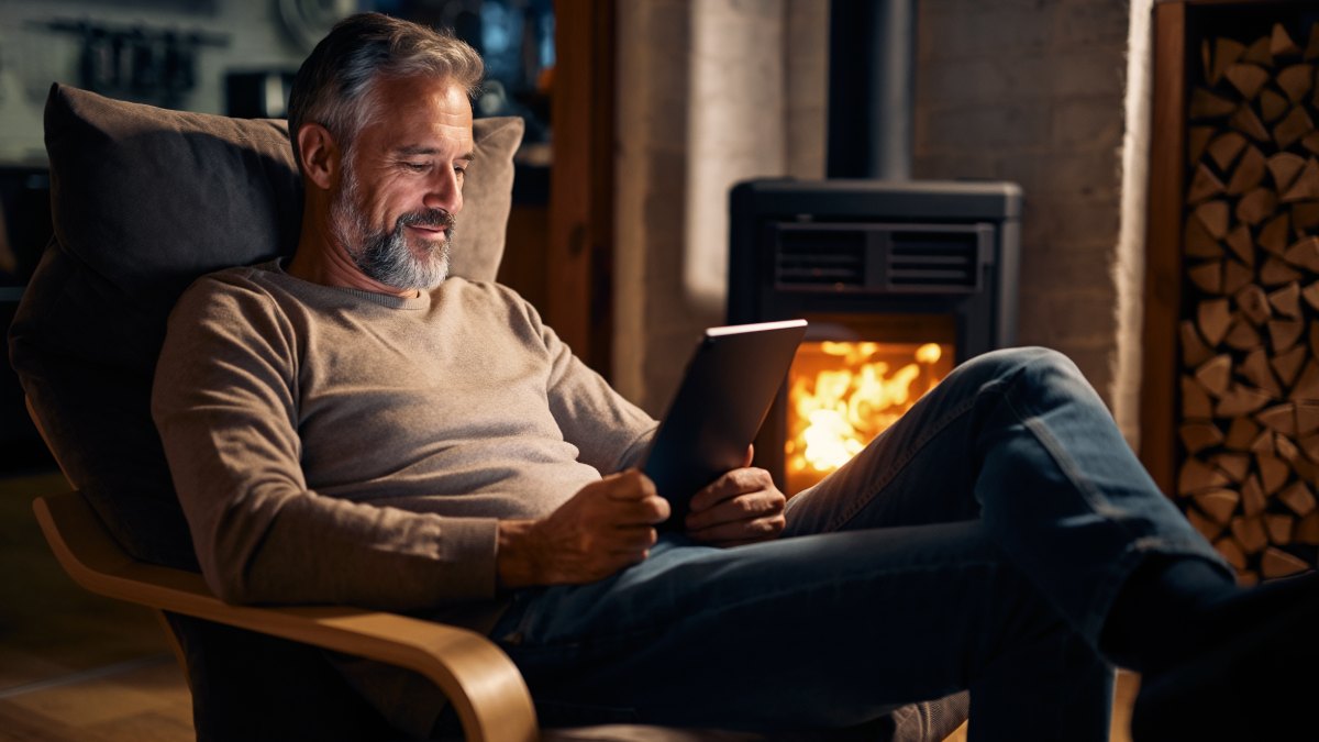 homme sur sa tablette devant son poêle à bois