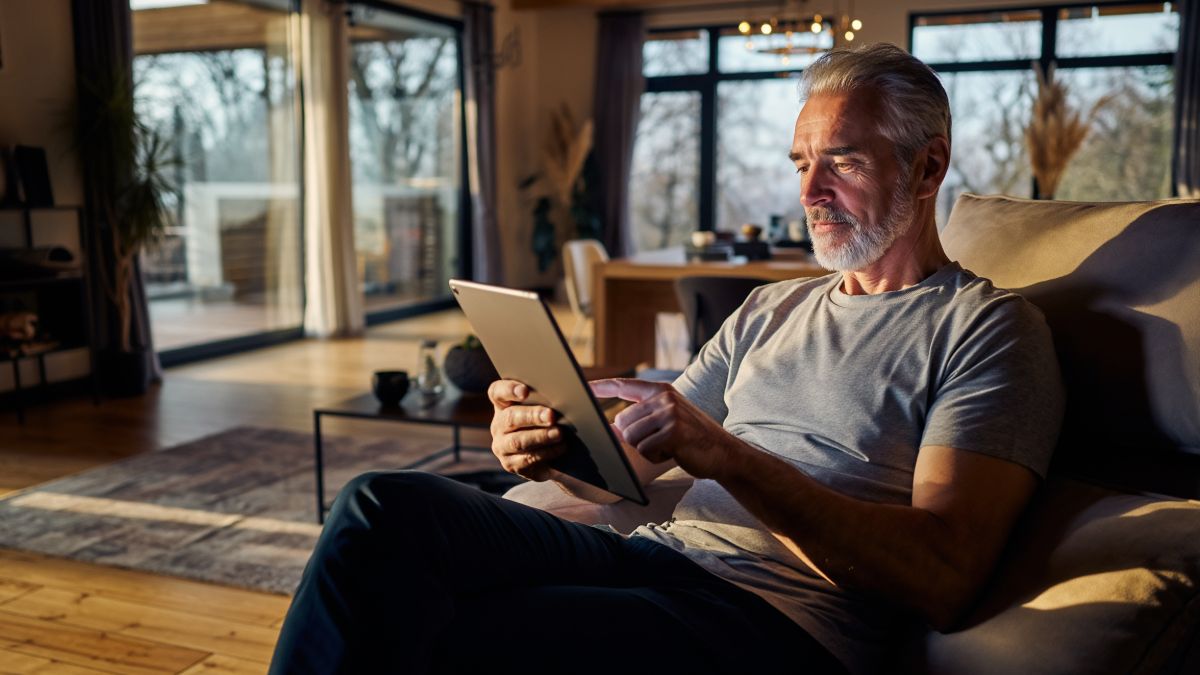 homme dans son salon sur sa tablette